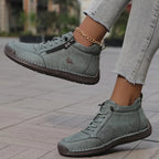 Sage green ankle boots shown close up highlighting the stitched toe panel and chunky tan outsole