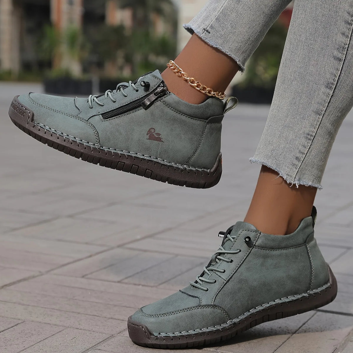 Sage green ankle boots shown close up highlighting the stitched toe panel and chunky tan outsole