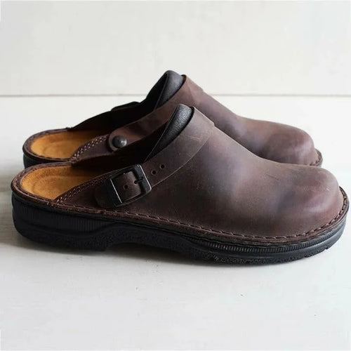 Side view of dark brown weathered leather clog with buckle strap and black cushioned sole