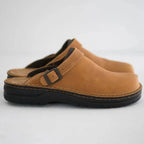Side profile of tan leather clog showing buckle strap, stitched trim and black sole