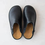 Top-down view of a pair of black leather clogs showing tan leather footbed and rounded toe