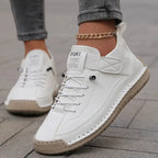 White leather sneaker with lace-up front, visible hand-stitched trim, and gold anklet chain worn on foot