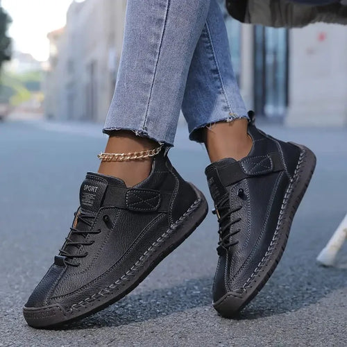 Side view of black leather sneaker showing elastic hook-and-loop strap and contrast topstitching