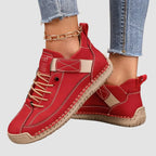 Angled view of red leather sneakers with cream laces and contrast stitching on a plain background