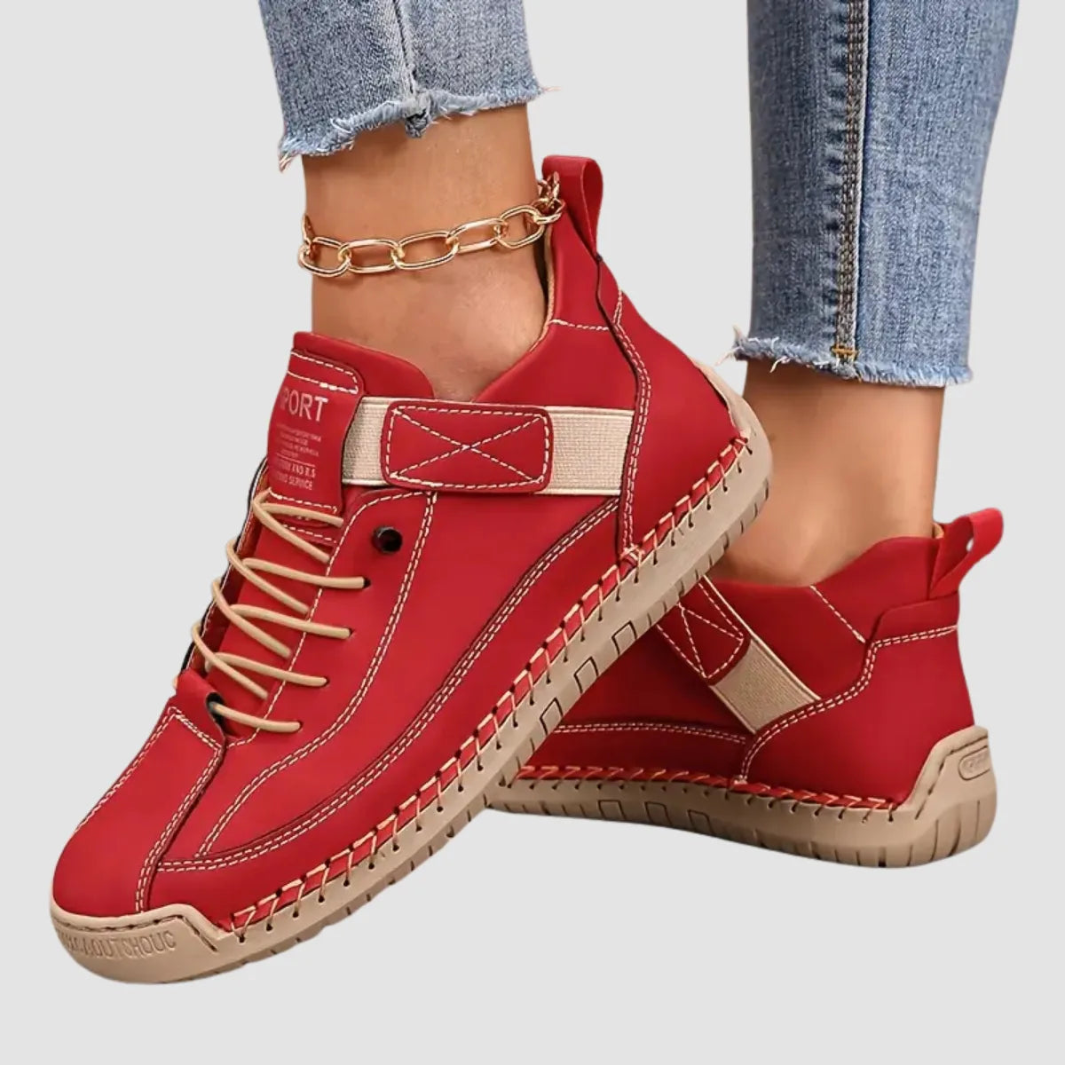 Angled view of red leather sneakers with cream laces and contrast stitching on a plain background
