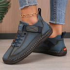 Blue-grey leather sneaker pair with orange heel tab and visible decorative seam stitching