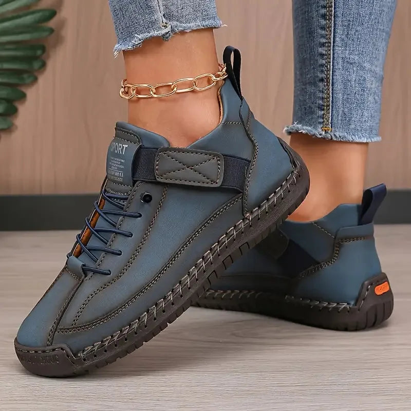Blue-grey leather sneaker pair with orange heel tab and visible decorative seam stitching