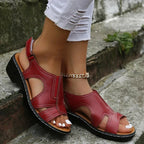 Deep red leather wedge sandal with cut-out panels and adjustable ankle buckle, close side view