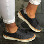 Charcoal grey perforated suede slip-ons with tan cork sole and metallic heel tab, close-up side profile