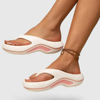 Side view of white thong-strap platform sandal with soft pink wavy sole detail worn on foot