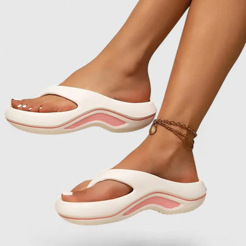 Side view of white thong-strap platform sandal with soft pink wavy sole detail worn on foot