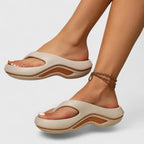 Side profile of beige thong-strap platform sandal with tan wavy midsole trim worn on foot
