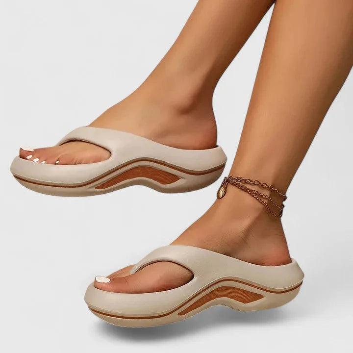 Side profile of beige thong-strap platform sandal with tan wavy midsole trim worn on foot