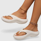 Side view of off-white thong-strap platform sandal with matching tonal wavy sole worn on foot