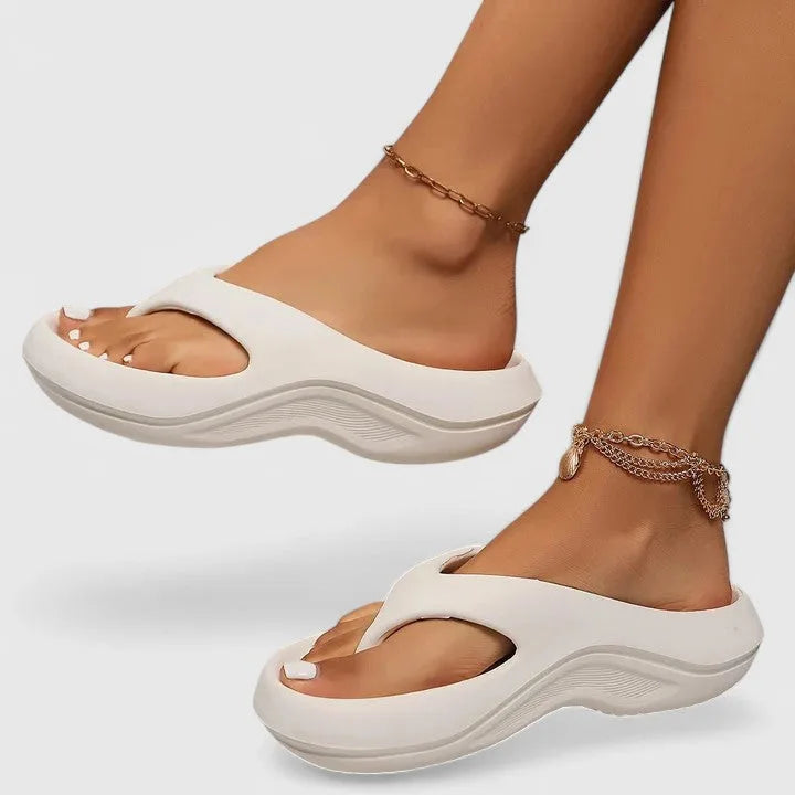 Side view of off-white thong-strap platform sandal with matching tonal wavy sole worn on foot