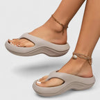 Side profile of grey thong-strap platform sandal with matching grey wavy sole worn on foot