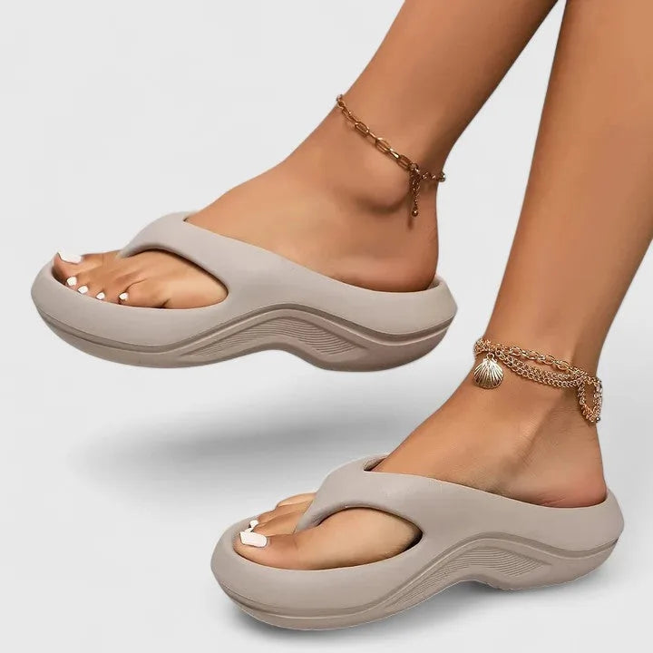 Side profile of grey thong-strap platform sandal with matching grey wavy sole worn on foot