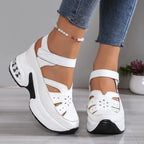 Close-up side profile of white platform sandal with Velcro ankle strap and perforated floral cut-outs