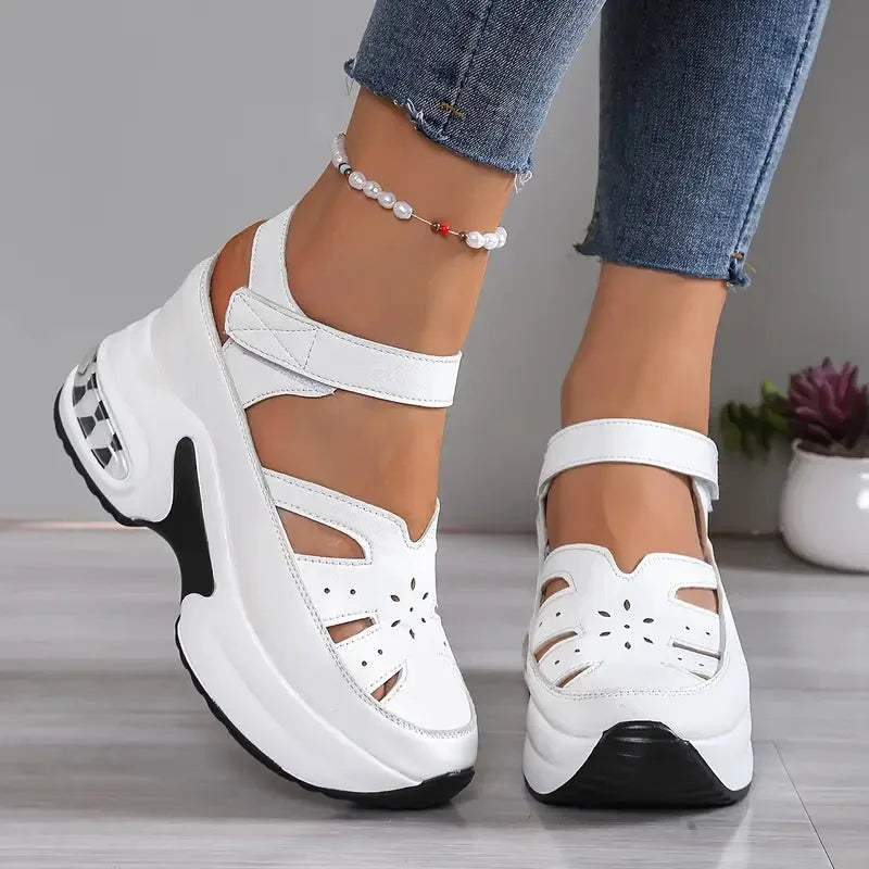 Close-up side profile of white platform sandal with Velcro ankle strap and perforated floral cut-outs