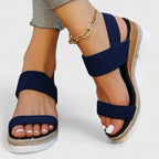 Close-up of navy blue wedge sandal with ribbed elastic straps and espadrille wrapped wedge heel