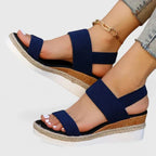 Pink wedge sandal worn from behind, showing the open heel, ankle strap and chain anklet