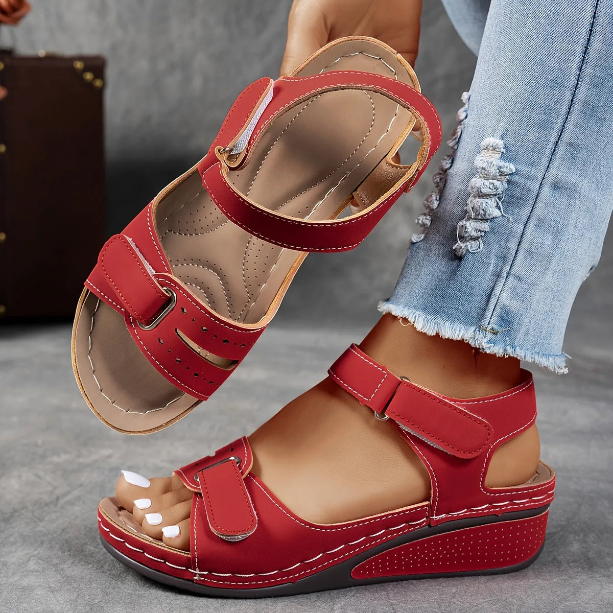 Red wedge sandal with adjustable straps and stitched detailing, paired with ripped jeans to show everyday styling