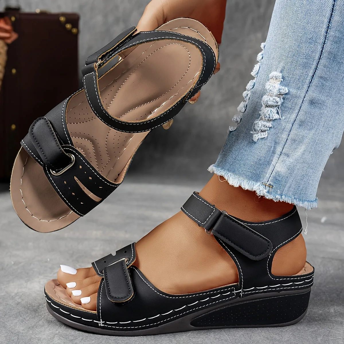 Black wedge sandal with contrast stitching and dual adjustable straps, showing the ankle fit from the side