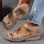 Beige wedge sandal with open toe and ankle strap, photographed on foot to show the natural fit and low heel