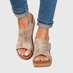 Front view of beige distressed leather wedge sandals with cork platform heel and peep toe, worn with cuffed jeans