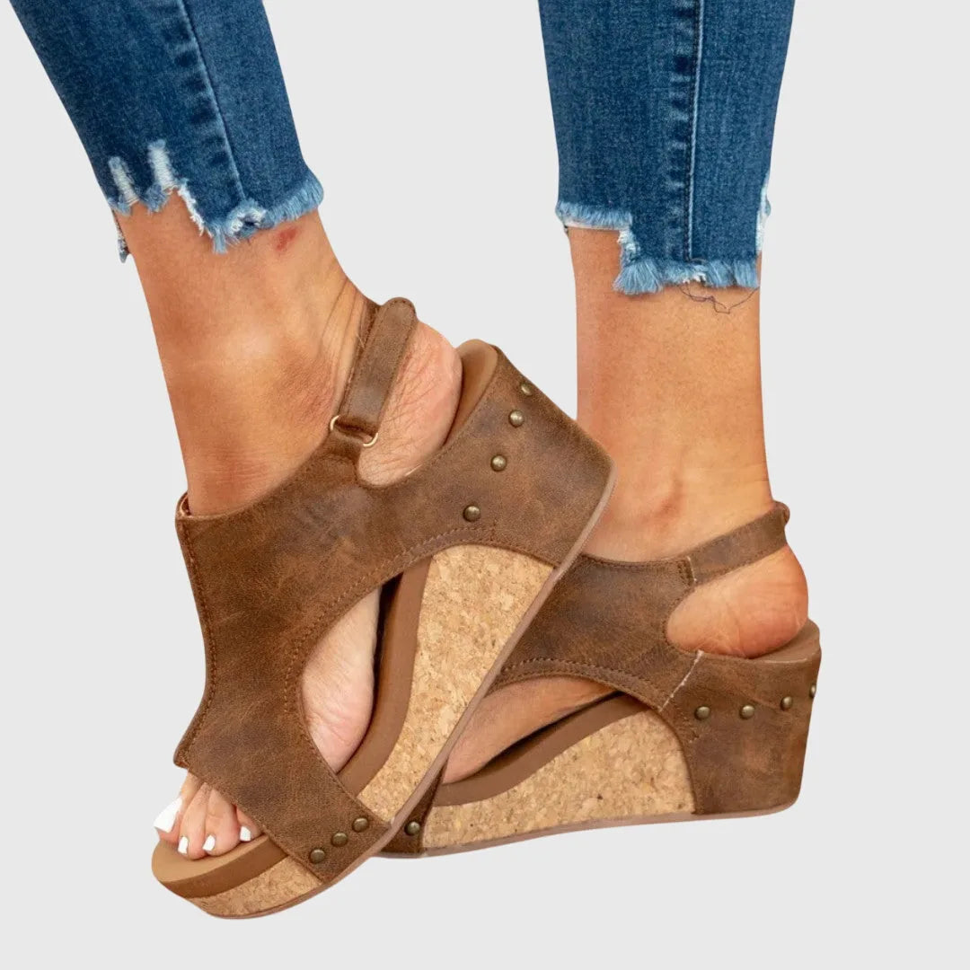 Close-up detail of cork wedge platform and stud trim on the beige sandal's heel cup