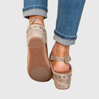 Back view of beige wedge sandals showing cork wedge sole, stud trim and adjustable ankle strap closure