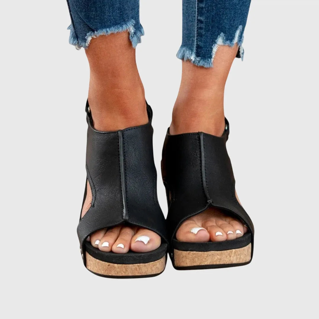 Close-up side view of beige sandal showing stud detailing along the heel counter and buckle strap