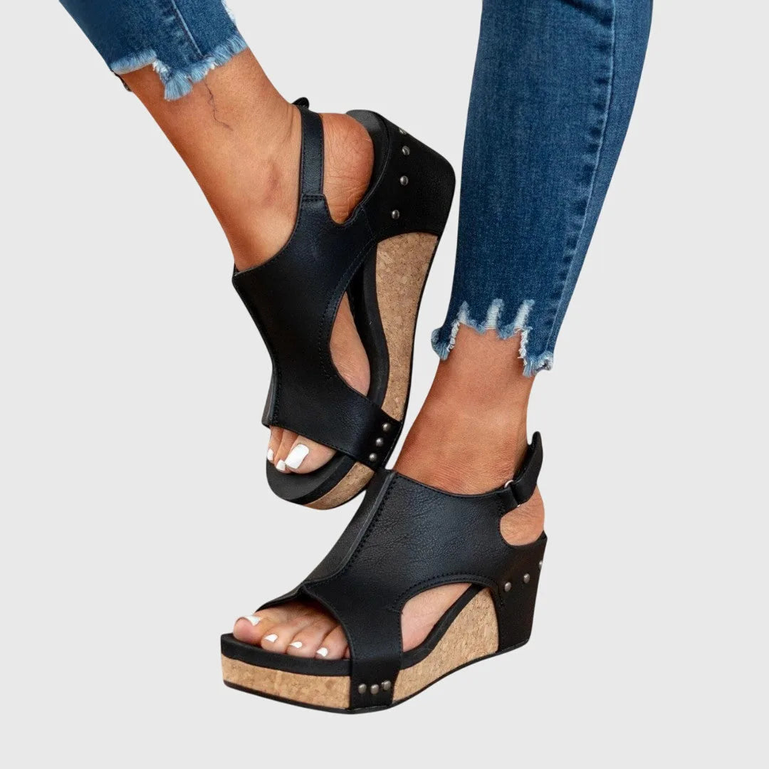 Angled front view of black sandals showing smooth leather upper, cut-out side panels and slingback strap