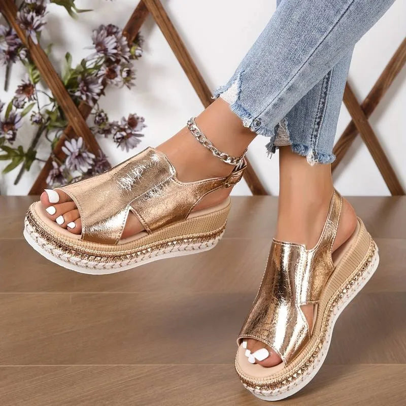 Pair of rose gold cutout wedge sandals worn with cropped jeans, showing crossover strap design