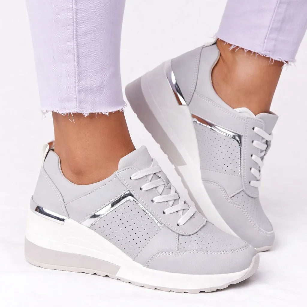 Grey wedge sneaker with silver mirrored trim and perforated side panel, worn with lilac cropped jeans