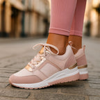 Side view of blush pink wedge sneakers with rose-gold trim and mesh texture, paired with ribbed pink leggings