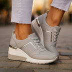 Grey wedge sneakers with silver metallic accent and lace-up front, styled with light denim jeans