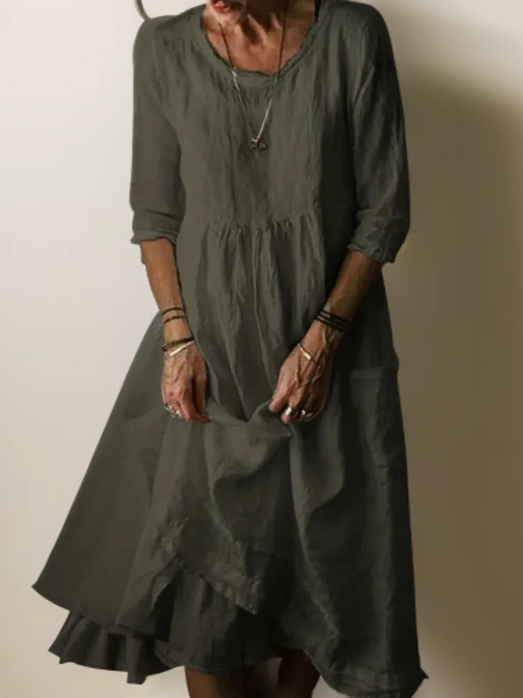 Olive green linen midi dress showing relaxed bodice gathers and flowy asymmetric hem