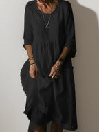 Black linen midi dress showing raw-edge neckline and loose A-line silhouette