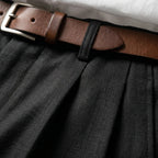 Close-up of the black linen waistband showing the pleat detail, fabric weave and a brown belt with silver buckle
