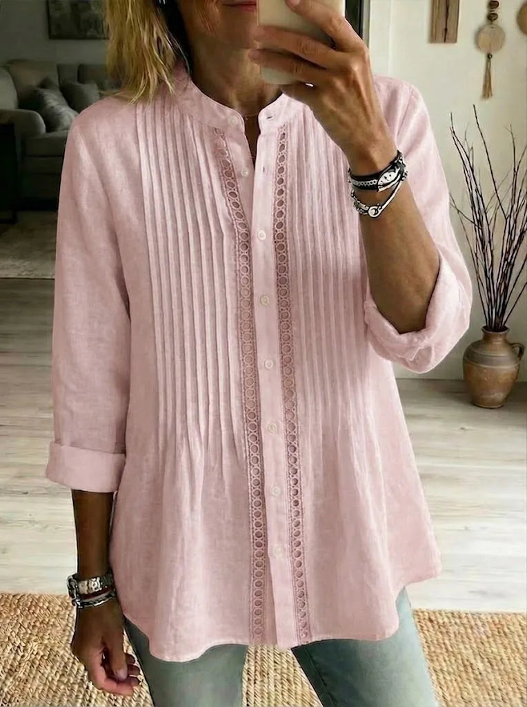 Close-up front view of a pink pintuck-pleated linen shirt with lace trim and button placket, worn with jeans.