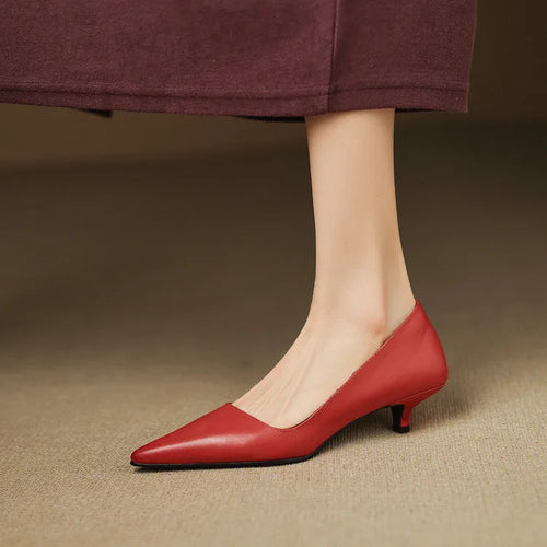 Side view of a red pointed-toe kitten heel pump worn with a maroon midi skirt, showing the slim low heel