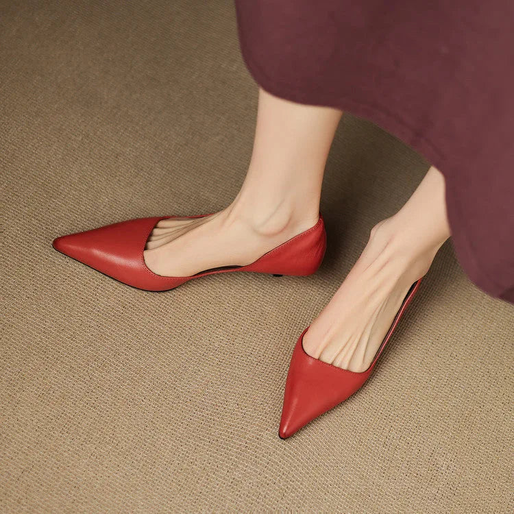 Top-down view of two feet wearing red pointed-toe heels crossed over each other on a jute rug