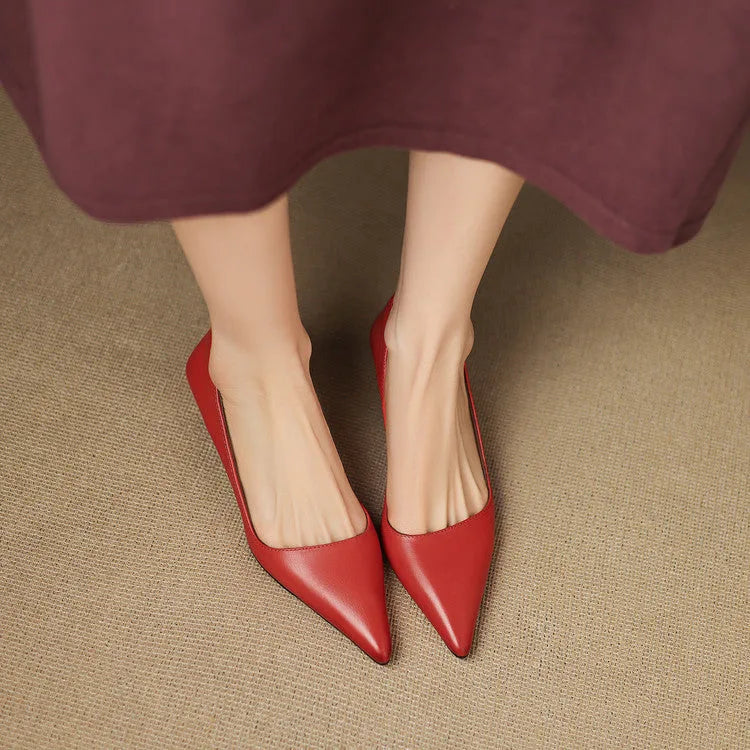 Front view of both feet in red pointed kitten heels peeking out from under a maroon dress