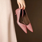Overhead shot of feet lifted in the air wearing red pointed-toe shoes against a plain brown backdrop