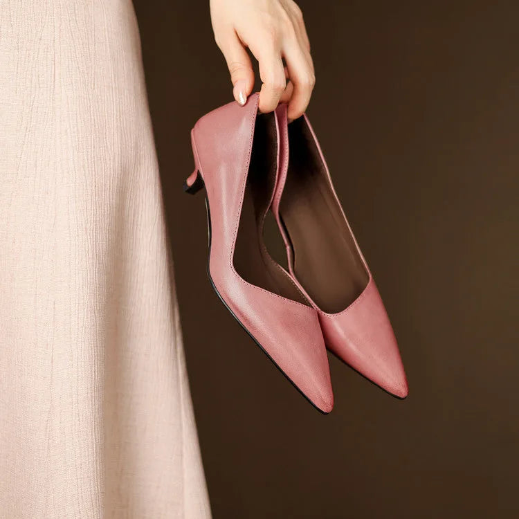 Overhead shot of feet lifted in the air wearing red pointed-toe shoes against a plain brown backdrop
