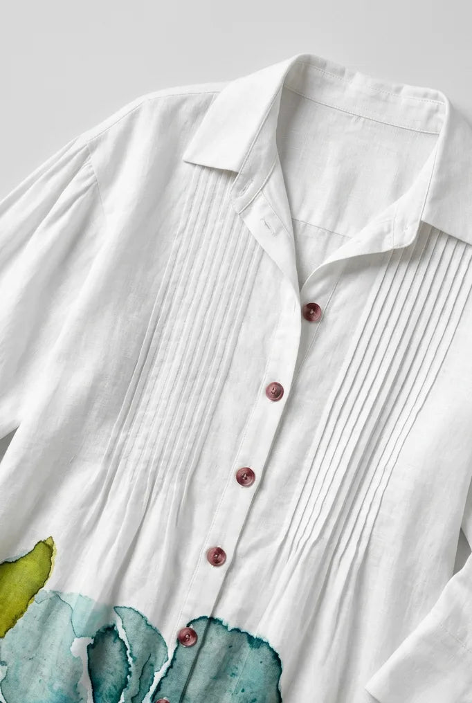 Close-up of the collar, pintuck pleating and mother-of-pearl style buttons on the white linen shirt dress
