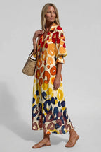 Woman wearing a cream shirt dress with a bold orange, red, yellow and navy abstract leopard-style print