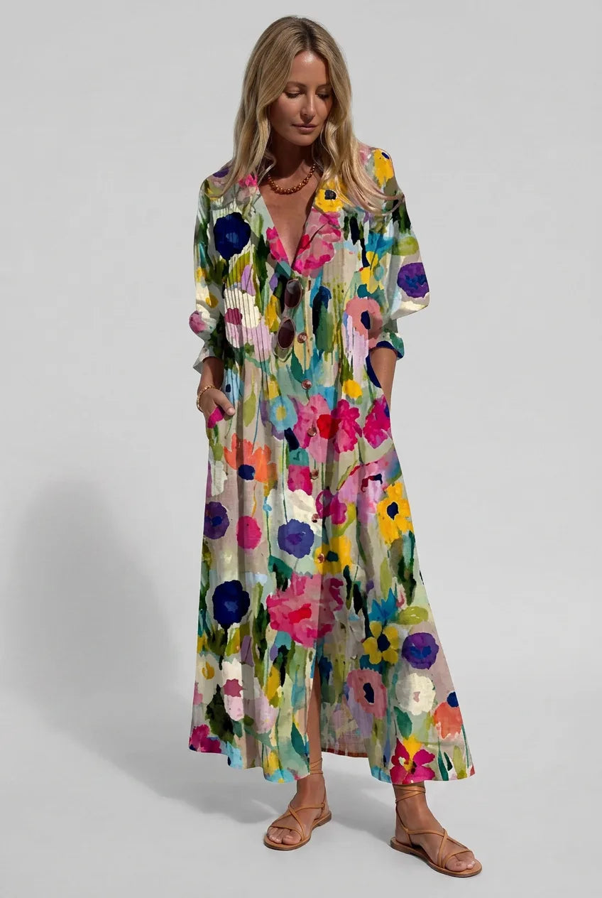 Woman in a multicoloured wildflower printed maxi shirt dress with pintuck bodice and side slit, hands in pockets