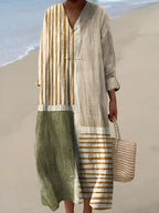 Striped linen-look midi dress in ochre, cream and sage colour-block panels, styled with a woven straw tote on the beach